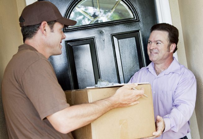 Man receiving a package delivery from a courier at his home.