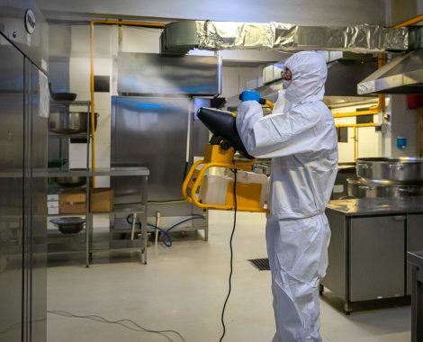 man in protective equipment disinfects with a spray gun industrial kitchen surfaces due to coronavirus covid-19 .Virus pandemic
